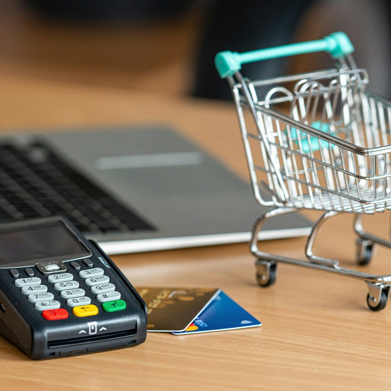 credit card terminal on table in the store with credit card, laptop and mini shopping cart on table